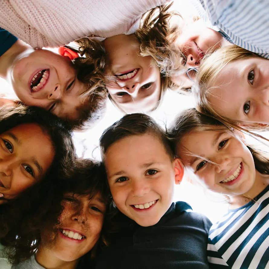 iStock-611288268.jpg mehrere Kinder die im Kreis zusammenstehen und lächeln